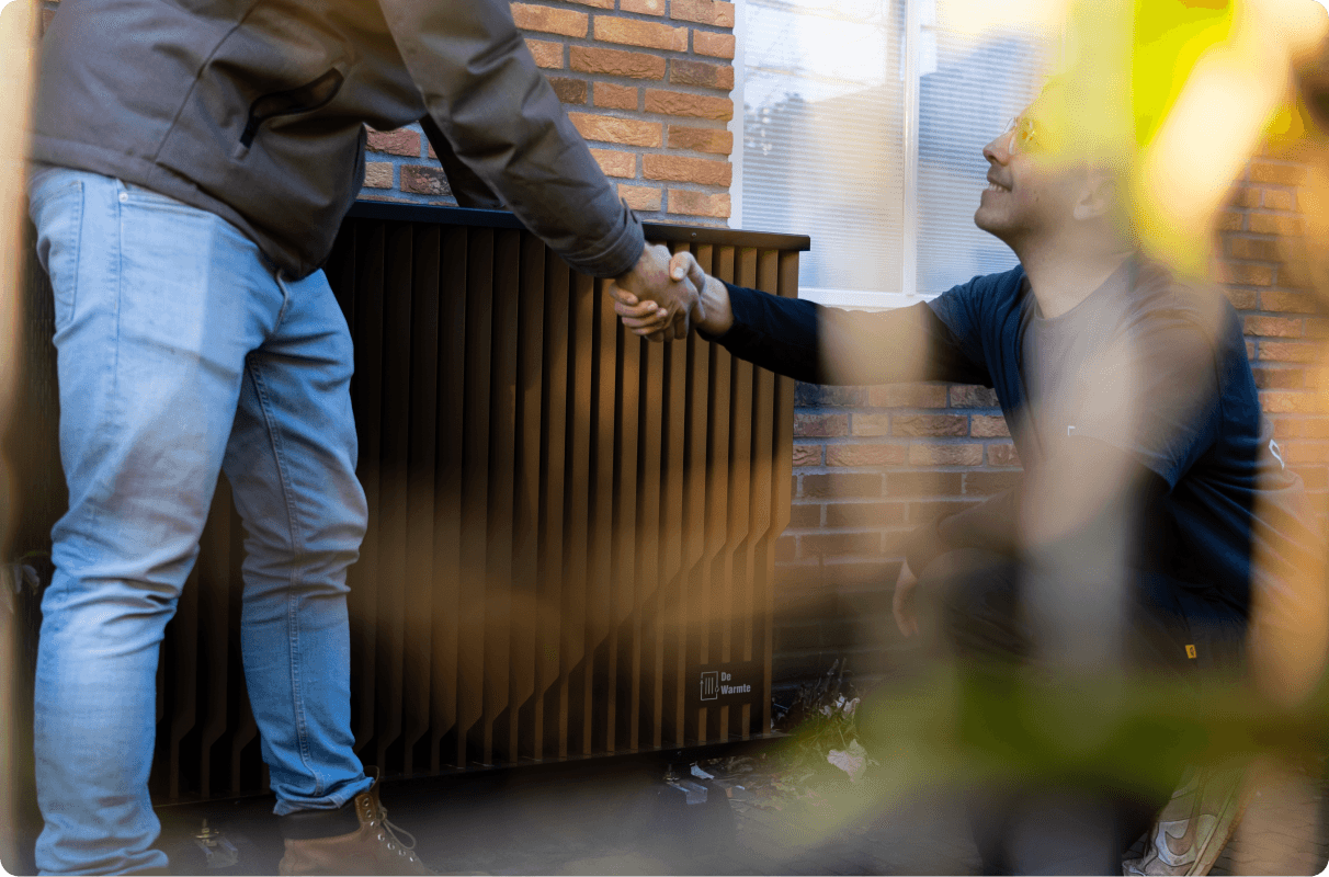 Een foto van onze installateur die bezig is met het installeren en afhandelen van de hybride warmtepomp Pomp-AO samen met de klant.