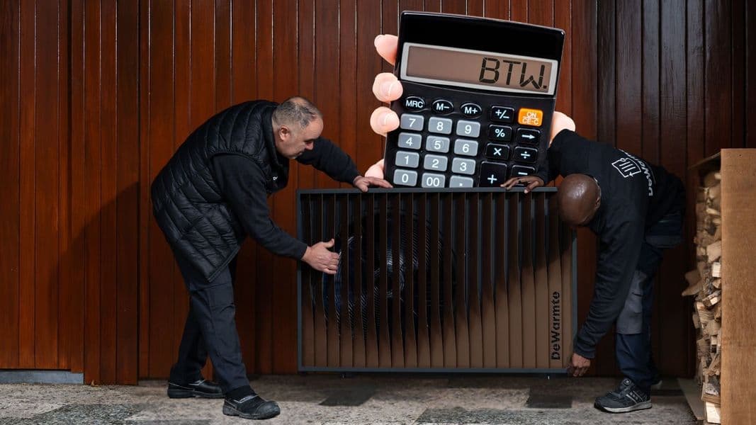 Two men install a large heat pump, with a giant novelty calculator showing "BTW" above it, against a wooden wall.