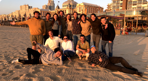 Teamfoto van DeWarmte tijdens een ontspannen teamuitje op het strand, waarbij medewerkers samen genieten van de zon en het zand.