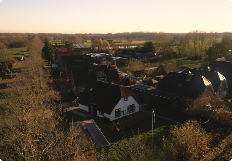 Een dronefoto van een huis met de Pomp-AO warmtepomp geïnstalleerd, te midden van een groene omgeving.